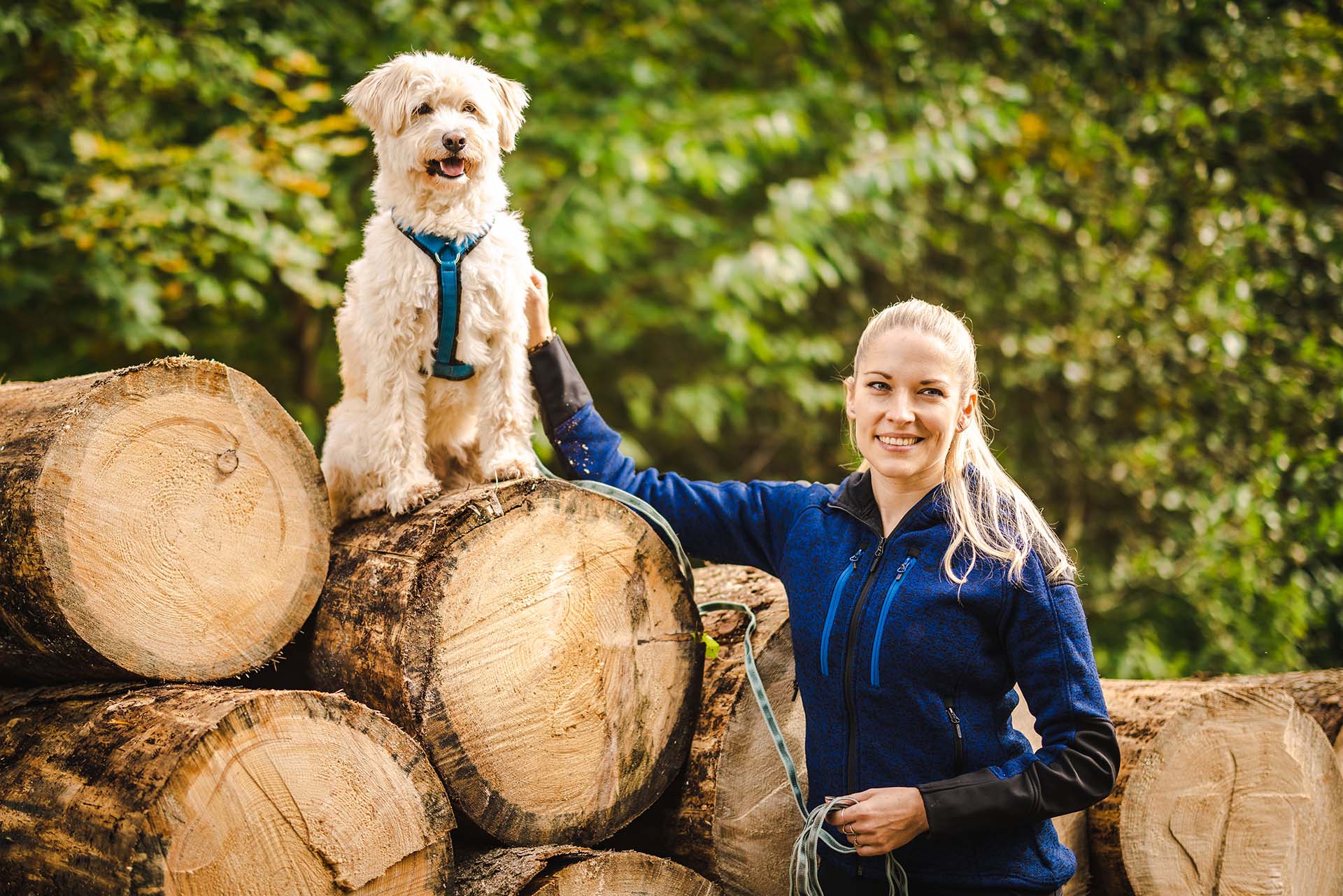 Hundetrainerin Conny und ihre Hündin Semmerl die auf einem Baumstumpf sitzt